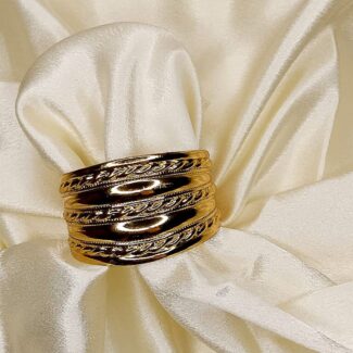 Gold stacked bangles with braided edges on ivory satin fabric.