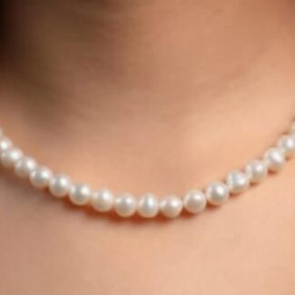 Close-up of a single-strand pearl necklace draped along the neck and collarbone.