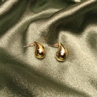 Pair of gold teardrop-shaped earrings resting on green satin fabric