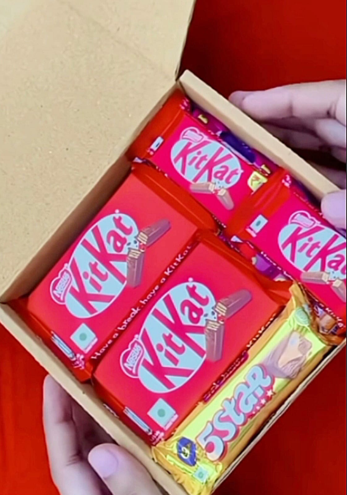Box of red-wrapped KitKat chocolate bars arranged in a wooden box.