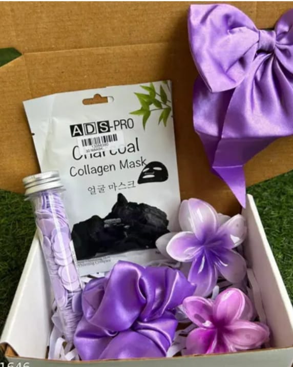 Gift box with purple satin bow, beauty products, and decorative purple flowers; includes ADS Pro Collagen Mask packet and a lavender bottle.