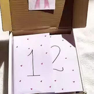 Card with the number 12 and small hearts inside an open cardboard box (gift box). зб