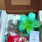 Gift box with a red KitKat bar, a bright green plastic flower pinwheel, and a small note reading 'V FREE GIFT' inside.