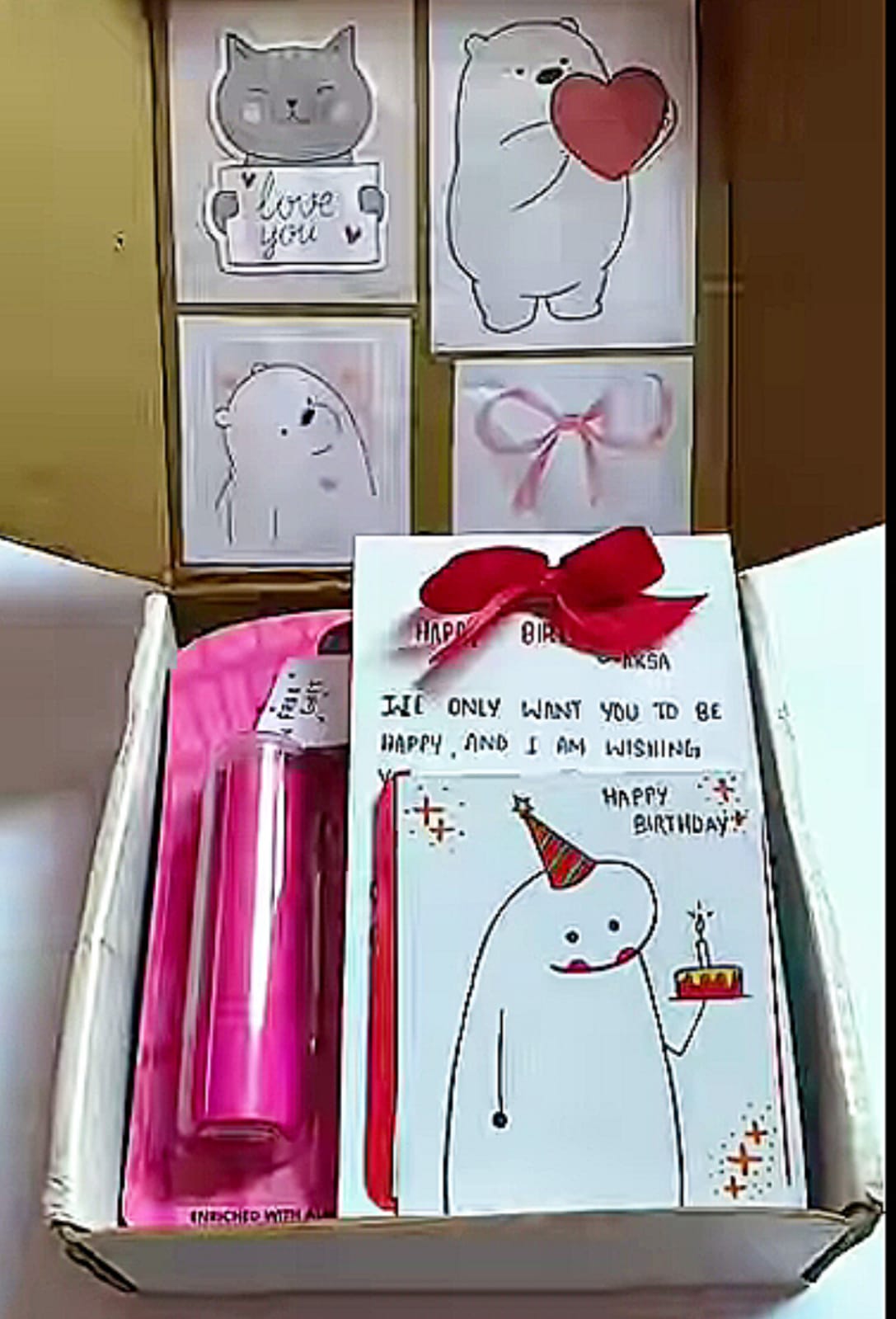 Gift box with greeting cards showing cute animal drawings, including a cat and a bear, and a birthday card with a red bow on top of the box.