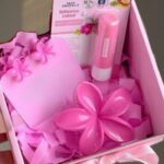 Pink gift set with flower-shaped decorations and beauty items (lotion, balm) in a pink box for gifting.