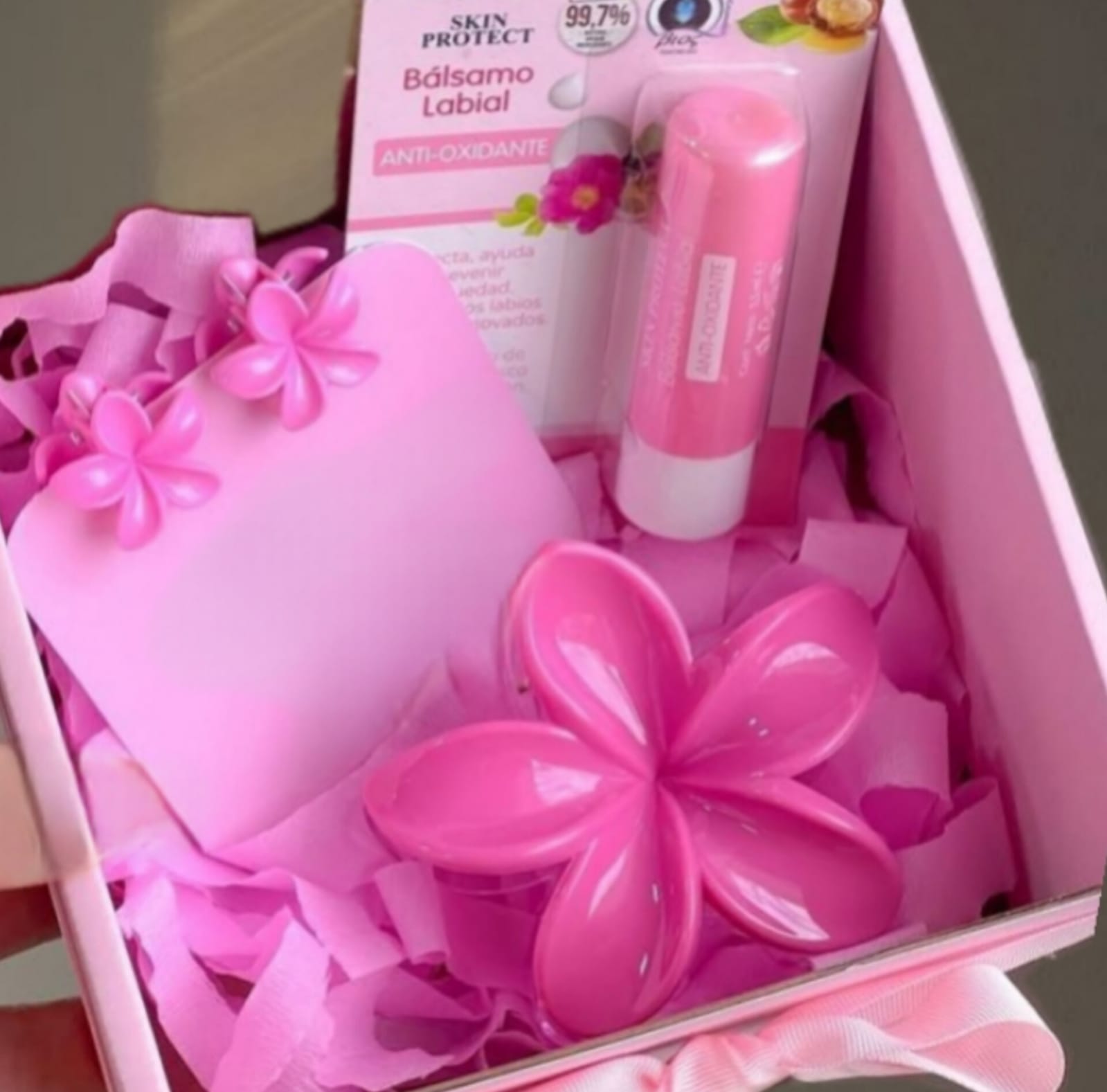 Pink gift set with flower-shaped decorations and beauty items (lotion, balm) in a pink box for gifting.