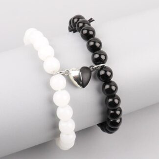 Two stretch bracelets—one white, one black—with a small silver heart charm, shown on a neutral display arm.