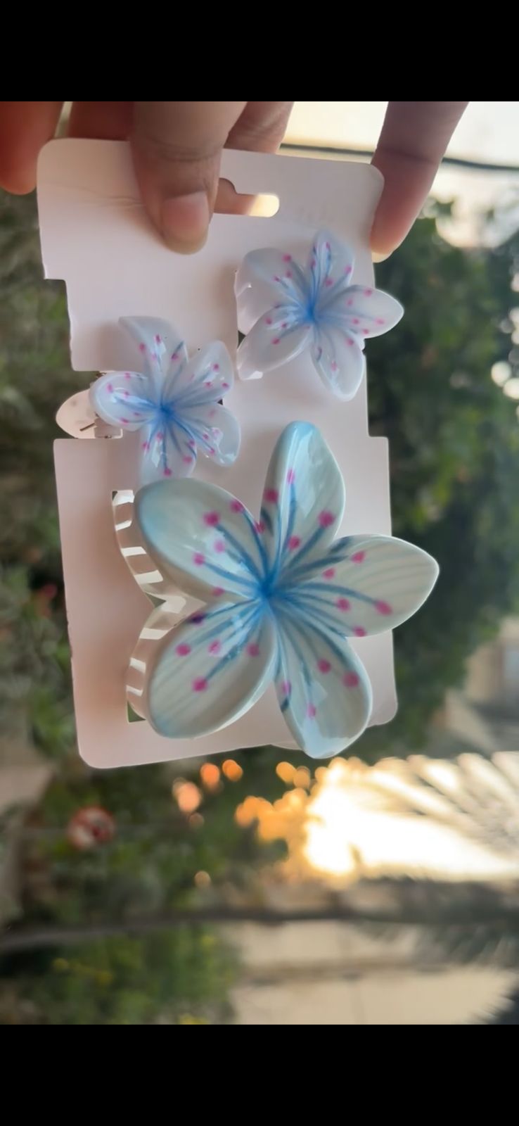 Three blue butterfly/flower hair clips attached to a white display card.