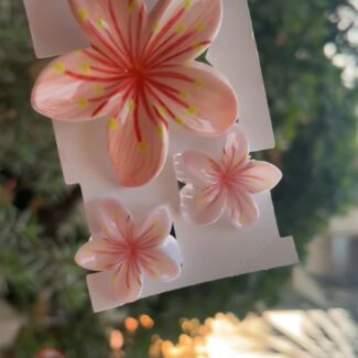 Hand holding a sheet of pink hibiscus flower stickers on white backing outdoors.