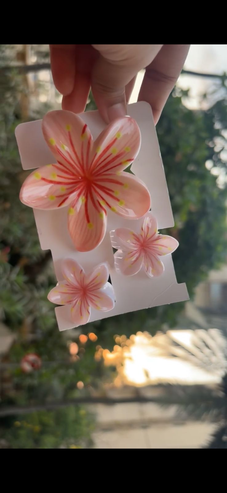 Hand holding a sheet of pink hibiscus flower stickers on white backing outdoors.