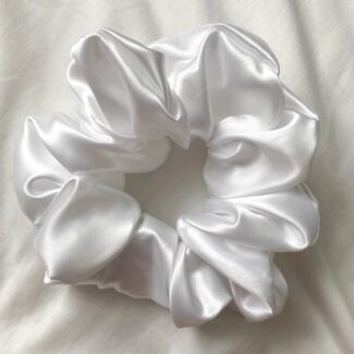 White satin hair scrunchie arranged in a circular shape on a light background