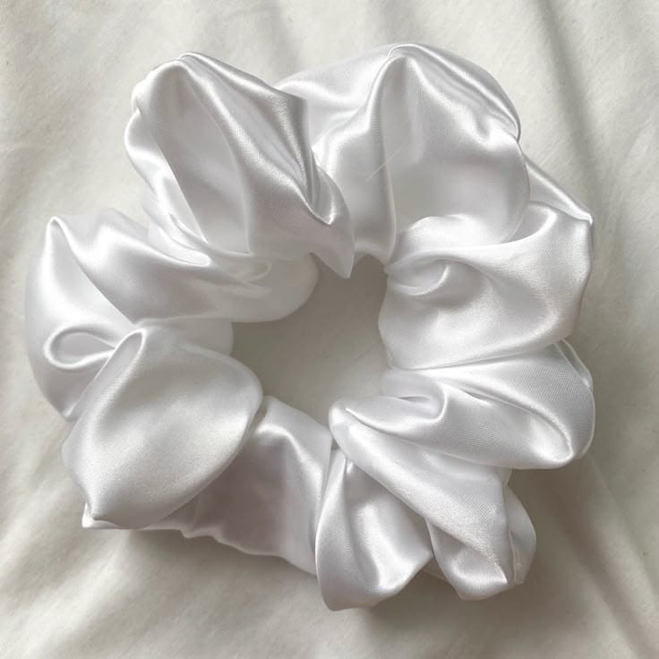 White satin hair scrunchie arranged in a circular shape on a light background